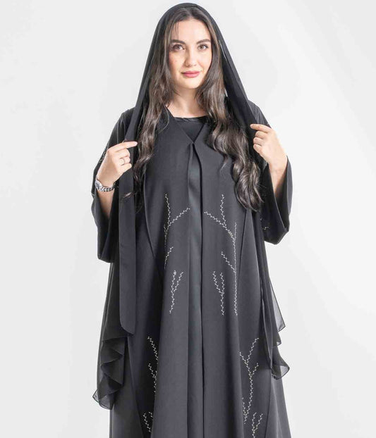 Woman wearing a black abaya with embroidery on a white background