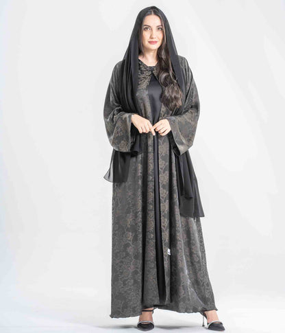 Woman wearing a long, dark gray dress with a matching hood on a white background