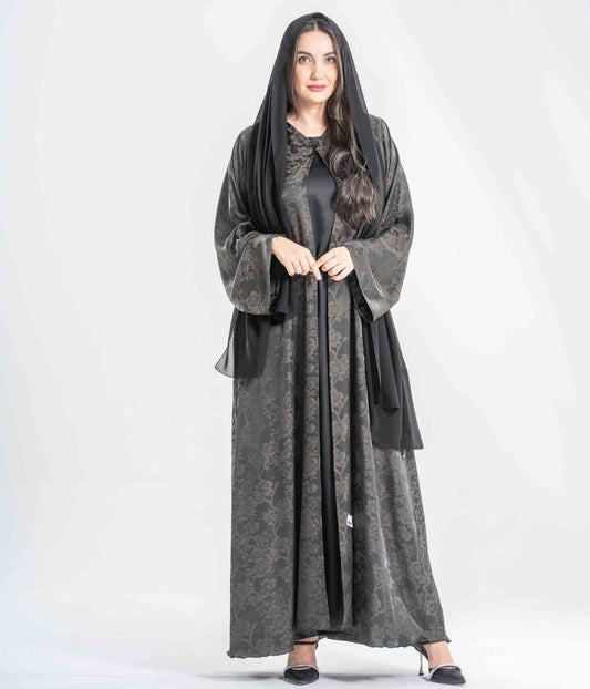 Woman wearing a long, dark gray dress with a matching hood on a white background